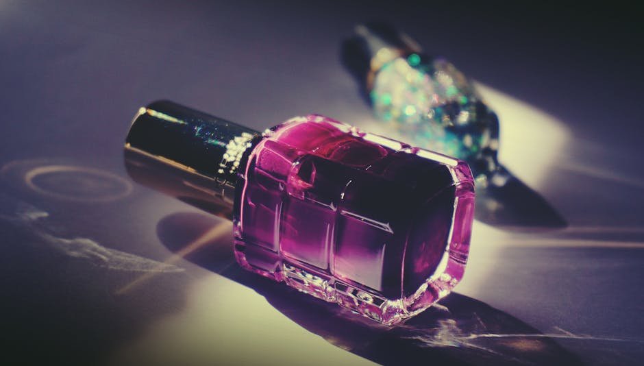 Artistic close-up of a pink nail polish bottle with reflective light and vivid colors.